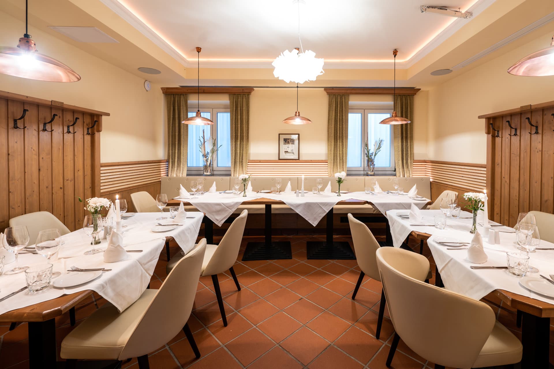 20220908_9307 Gemütlicher Essbereich im Stüberl „Friedrich-Adler“ mit eleganter Tischdekoration, weißen Tischdecken, Gläsern und Blumenarrangements, ideal für Familienfeste und kleinere Firmenfeiern in Das Chadim.