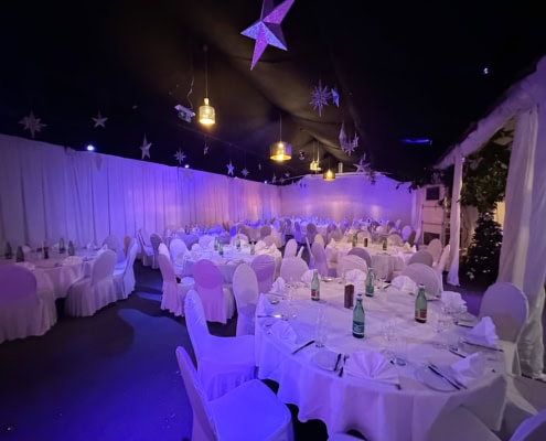 20231124_162057825_iOS Festzelt mit eleganter Dekoration, runden Tischen und weißen Stühlen, beleuchtet in sanften Farben für festliche Anlässe bei Das Chadim.