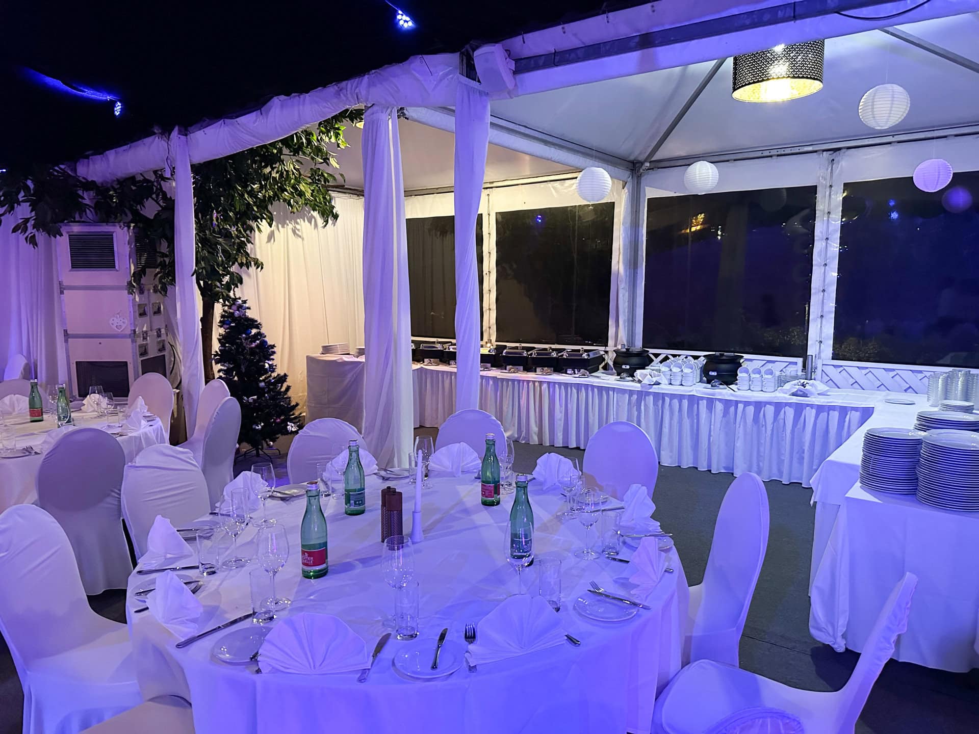 20231124_162301938_iOS Festzelt im Chadim mit eleganten runden Tischen, weißen Stuhlhussen, festlicher Beleuchtung und Buffetbereich, ideal für Veranstaltungen mit bis zu 120 Personen.