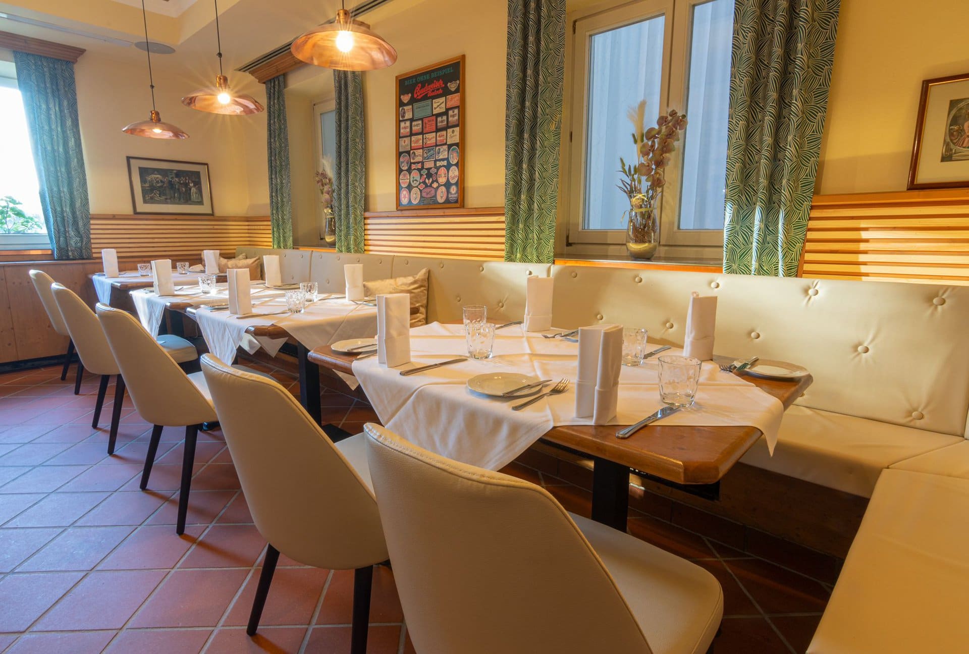 8f0c65a1-9d01-4d8c-b66b-15c99ad90137 Gemütlicher Speiseraum im Lokal Das Chadim mit eleganten Tischen, weißen Tischdecken und dekorativen Elementen, ideal für Veranstaltungen und Feiern.