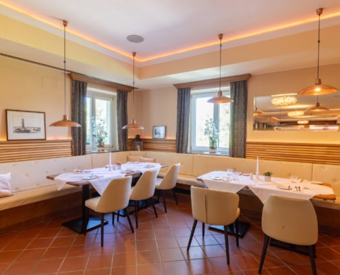 © Adrian Almasan | www.adrianalmasan.com Gemütlicher Speiseraum im Restaurant Das Chadim mit eleganten Tischen, modernen Pendelleuchten und Blick ins Grüne, ideal für Veranstaltungen und Familienfeiern.
