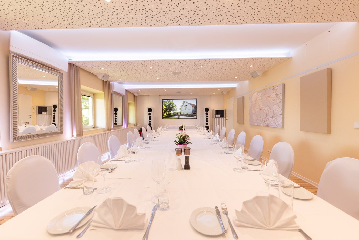 © Adrian Almasan | www.adrianalmasan.com Elegant gestalteter Bankettraum mit gedecktem Tisch, weißen Stühlen, akustisch optimierten Wänden und modernem HiFi-System, ideal für Feiern und Events im Das Chadim.