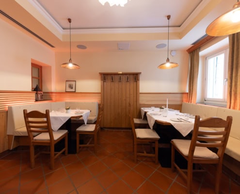 © Adrian Almasan | www.adrianalmasan.com Gemütlicher Speisebereich im Restaurant Das Chadim mit Holzmöbeln, Tischdecken und warmem Licht, geeignet für Familienfeste und kleinere Firmenfeiern.