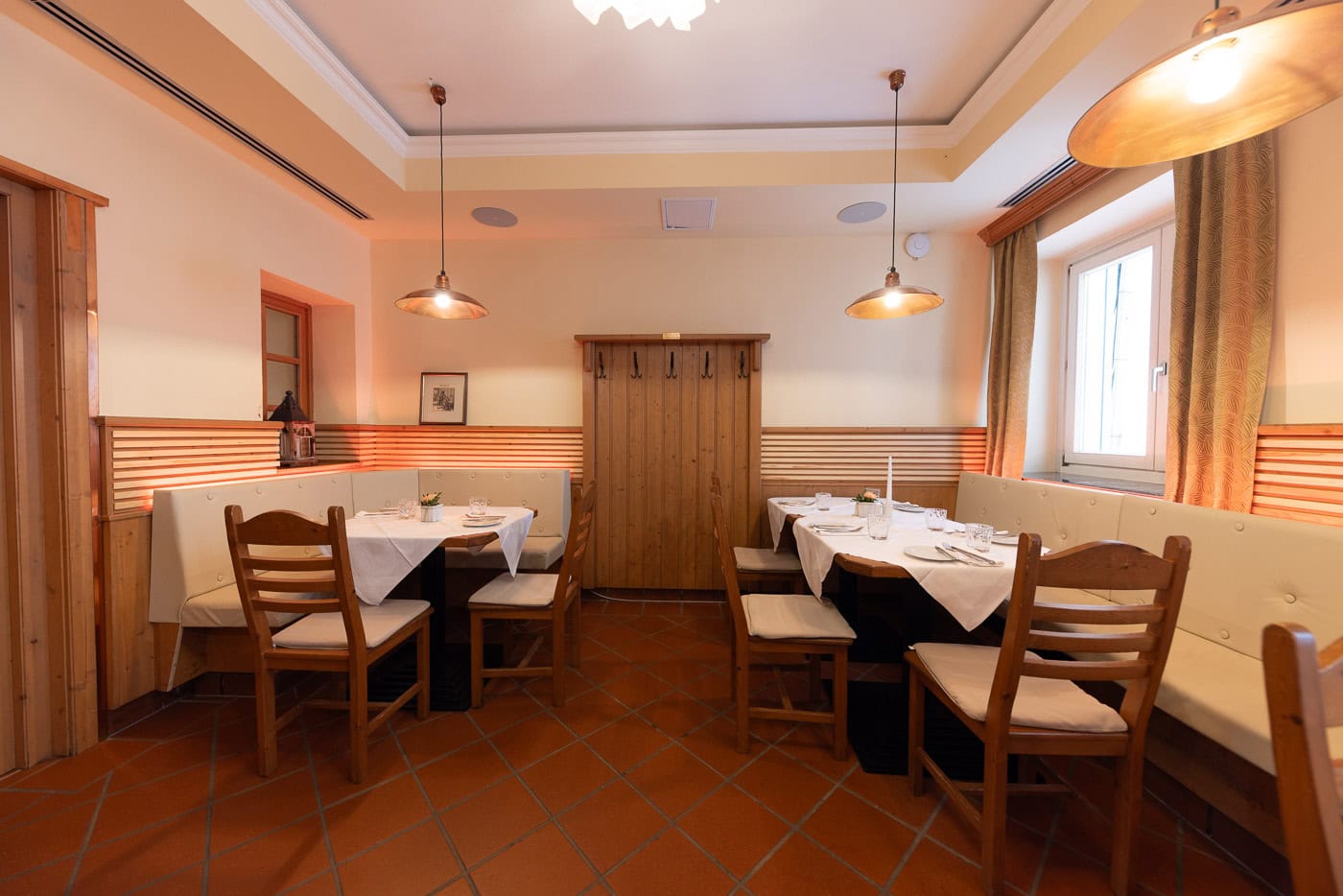 © Adrian Almasan | www.adrianalmasan.com Gemütlicher Speisebereich im Restaurant Das Chadim mit Holzmöbeln, Tischdecken und warmen Beleuchtungselementen, ideal für Familienfeiern oder kleinere Veranstaltungen.