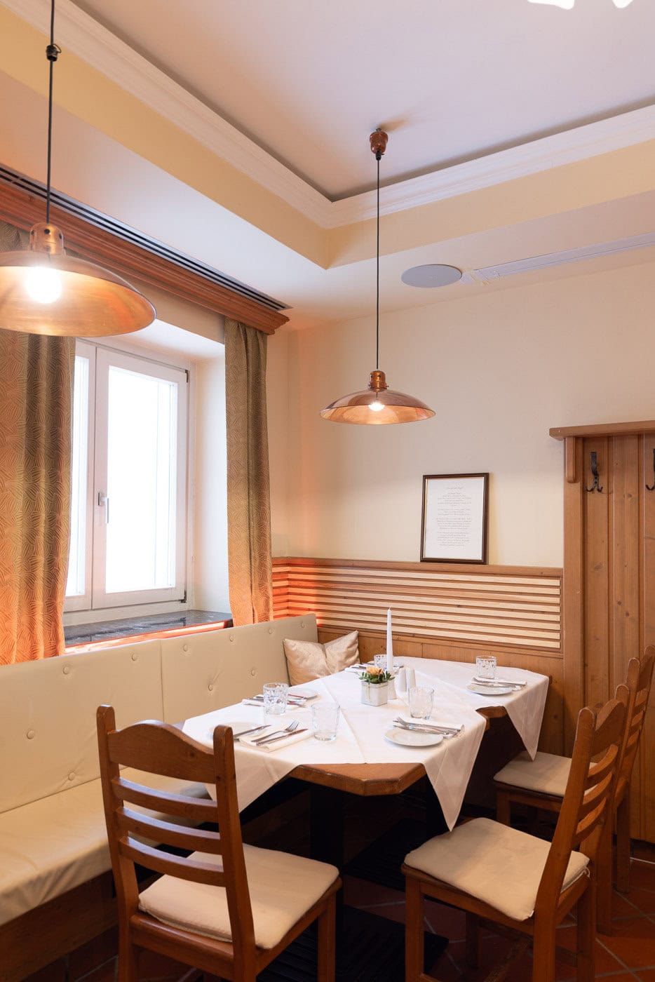 © Adrian Almasan | www.adrianalmasan.com Gemütlicher Essbereich im Restaurant Das Chadim mit Holzmöbeln, eleganter Tischdekoration und warmem Licht, ideal für Feste und Feiern.