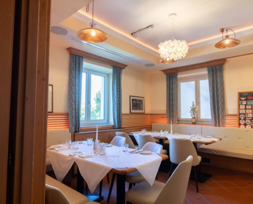 © Adrian Almasan | www.adrianalmasan.com Gemütlicher Speiseraum im Lokal Das Chadim mit eleganten Tischen, hellen Fenstern und warmem Licht, ideal für Veranstaltungen und Familienfeiern.