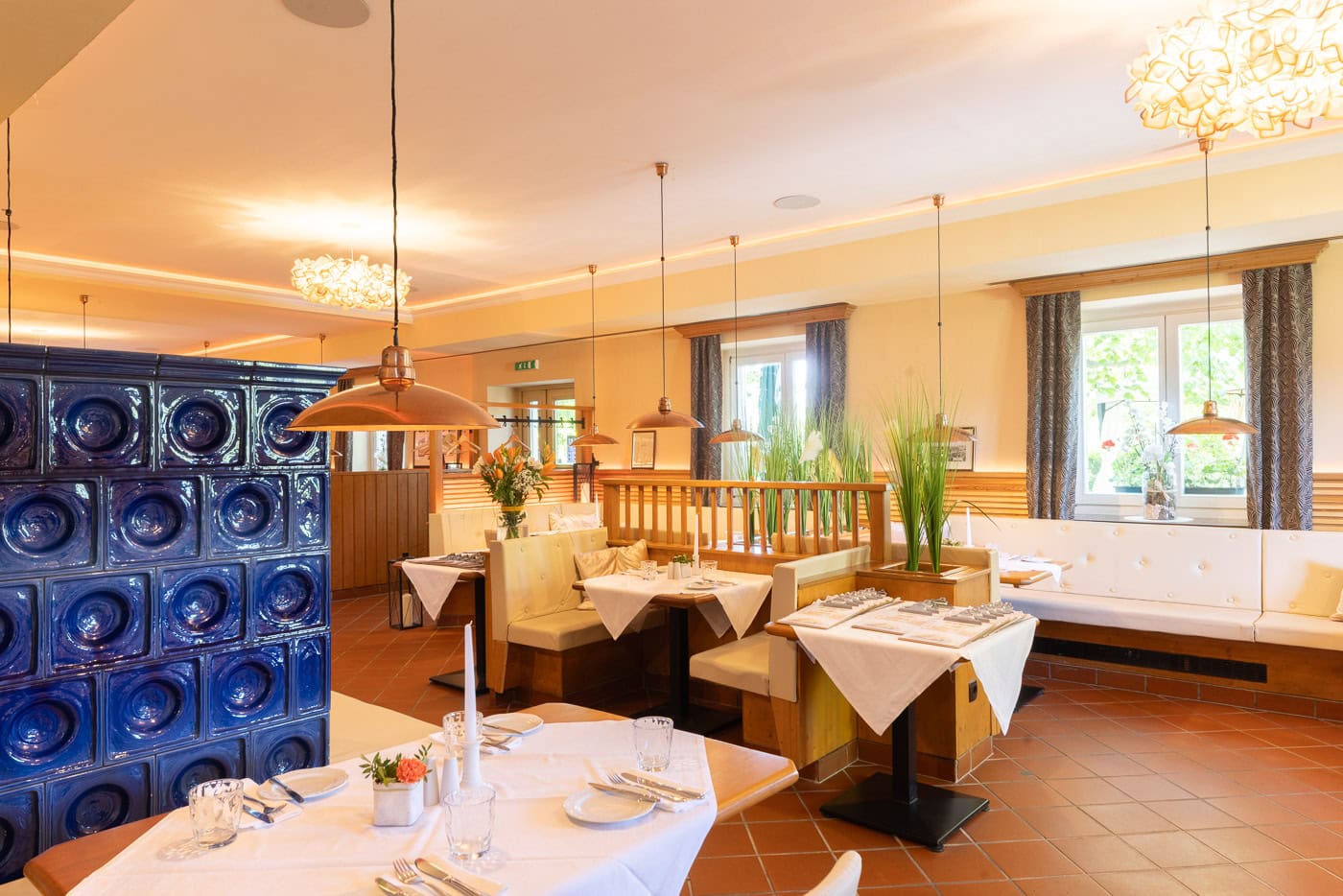 © Adrian Almasan | www.adrianalmasan.com Gemütliches Restaurantinterieur mit Holzmöbeln, eleganten Pendelleuchten, blauen Fliesen und gedeckten Tischen, ideal für Veranstaltungen und Feiern im Das Chadim.