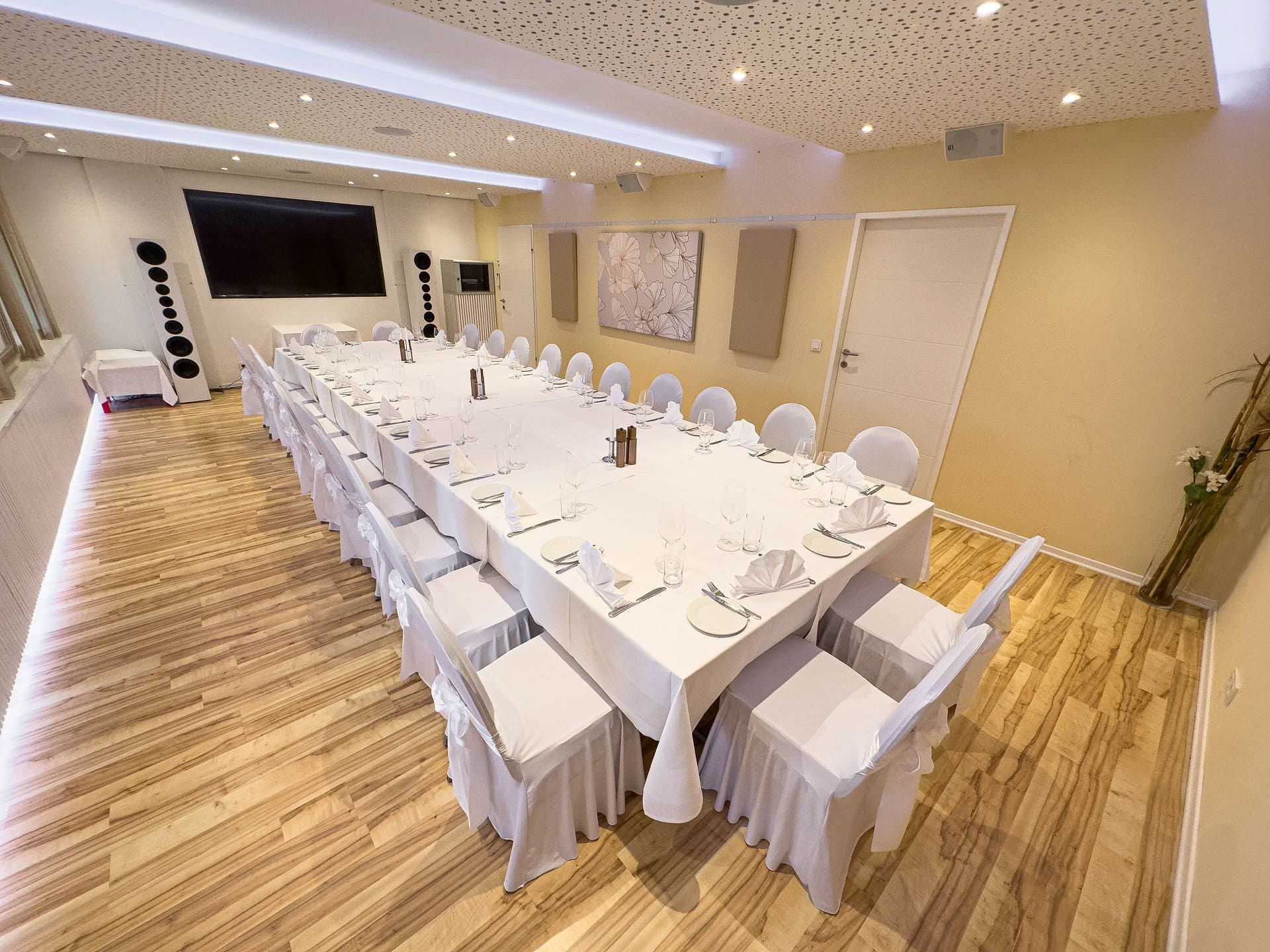 IMG_0758 Elegant Bankettraum mit langem Tisch, weißen Tischdecken, Gläsern und Akustiklautsprechern für hochwertige Veranstaltungen bei Das Chadim.