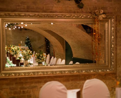 Spiegel_Gewölbe Historisches Gewölbe im Chadim, reflektiert im eleganten Spiegel, mit festlich dekorierten Tischen und Blumenarrangements, schafft eine besondere Atmosphäre für Veranstaltungen.