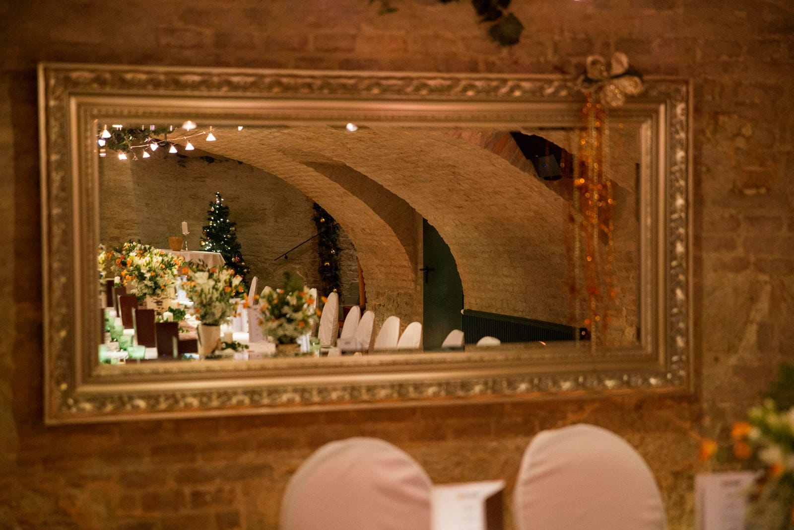 Spiegel_Gewölbe Spiegel im historischen Gewölbe von Das Chadim, reflektierende Atmosphäre mit festlich dekorierten Tischen und Blumenarrangements.